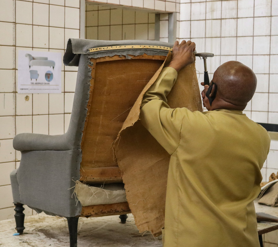 Craftsman upholstering a chair by hand